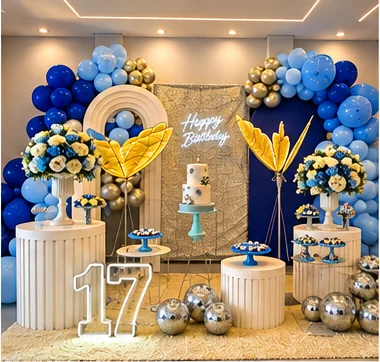 Decoração de 17 anos em azul, branco e dourado com arranjos de flores
