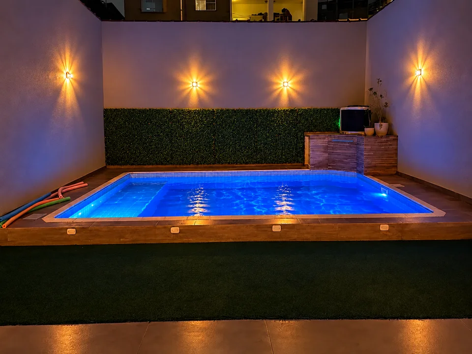 Piscina iluminada do Lugami à noite, com luz azul e arandelas