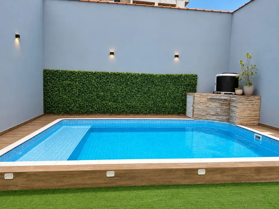 Piscina aquecida do Lugami com parede de folhagem e borda em madeira